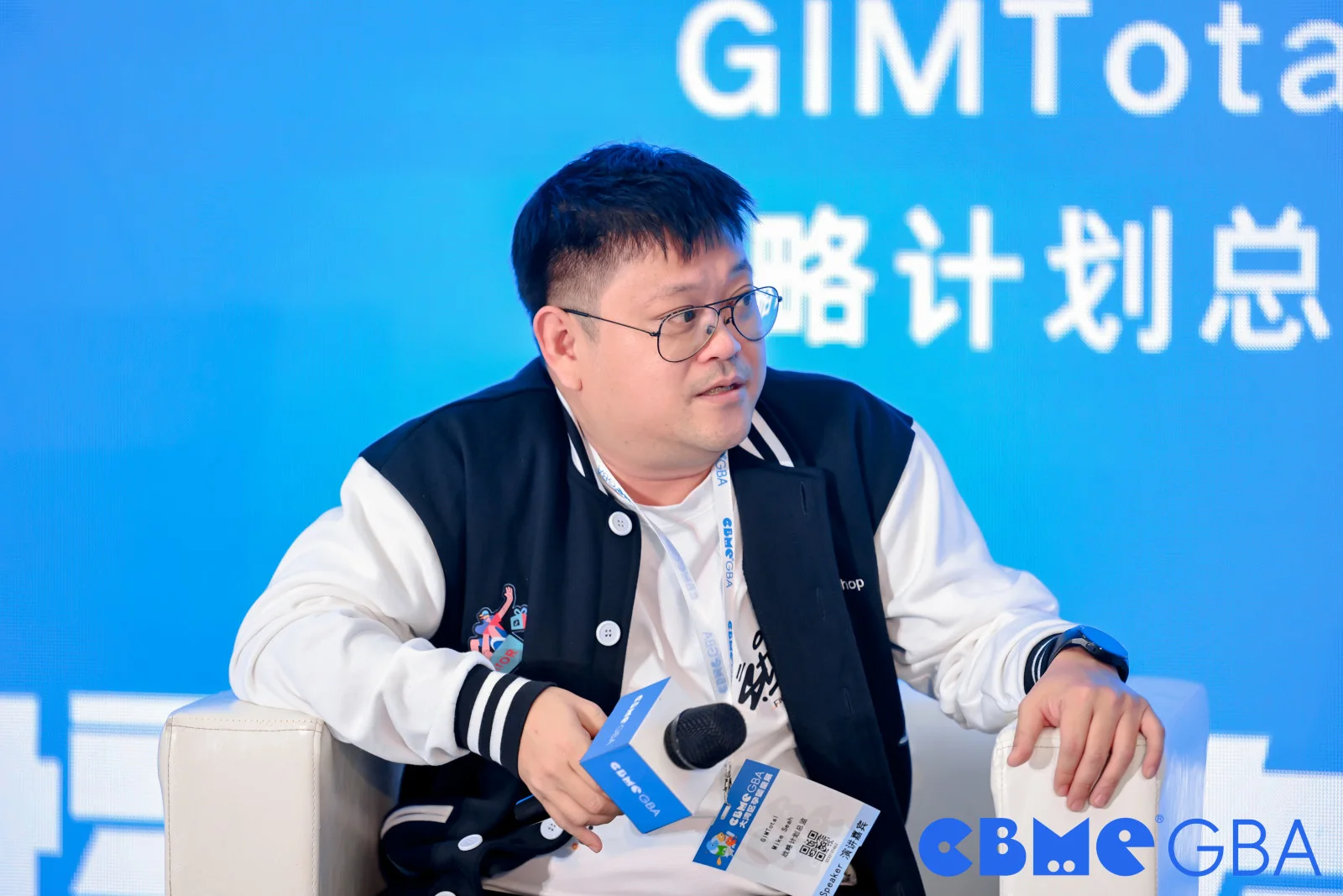 Mike duduk dengan mikrofon semasa perbincangan panel di pentas.