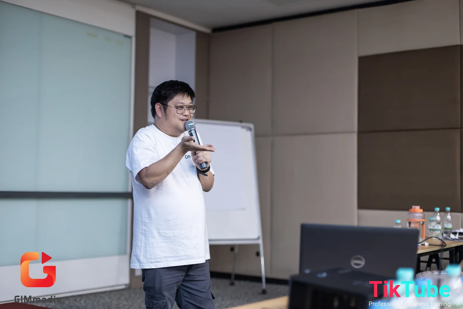 Mike memegang mikrofon sambil berbicara dengan peserta di dalam bilik bengkel.