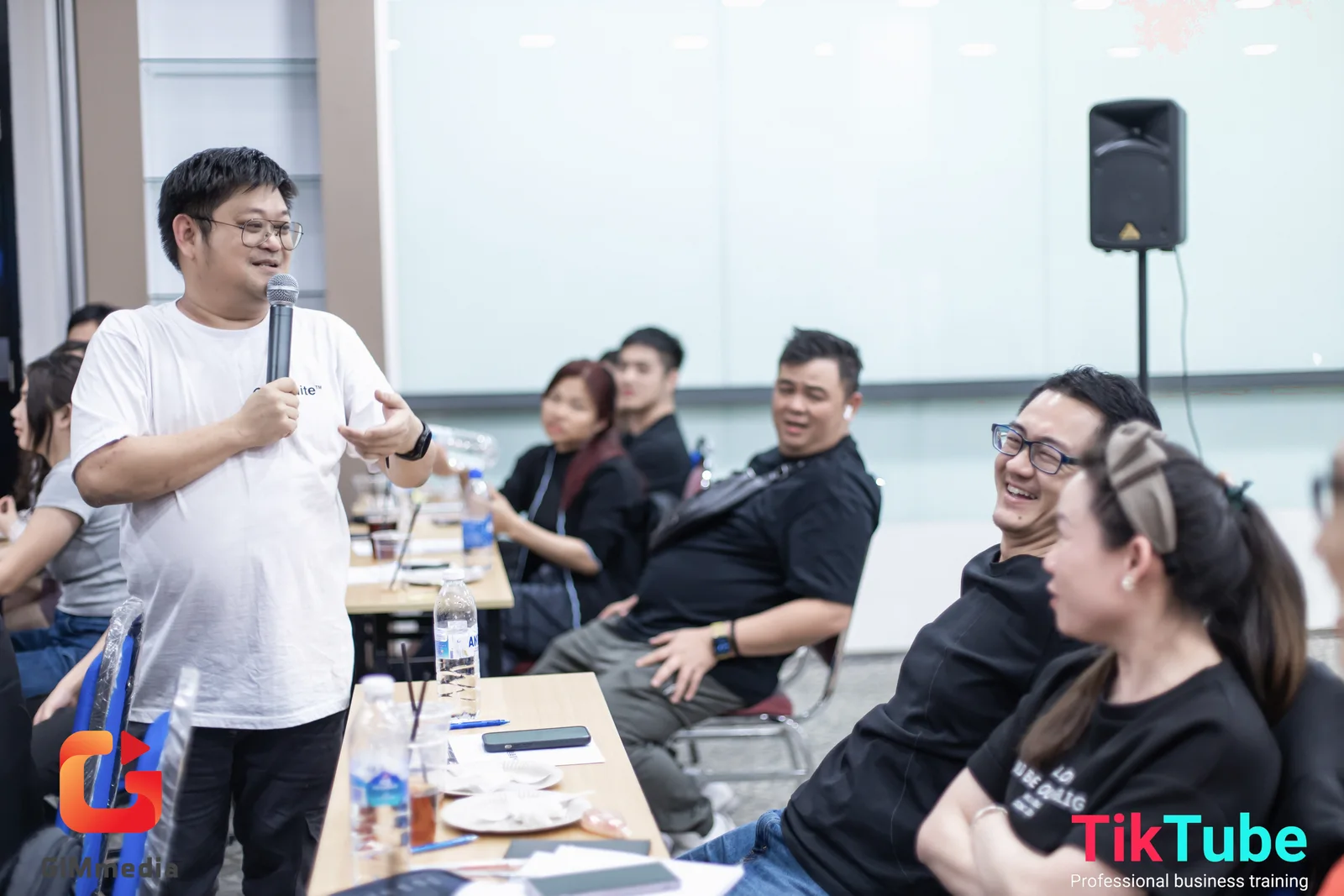 Mike memegang mikrofon sambil berbicara dengan peserta di dalam bilik bengkel.